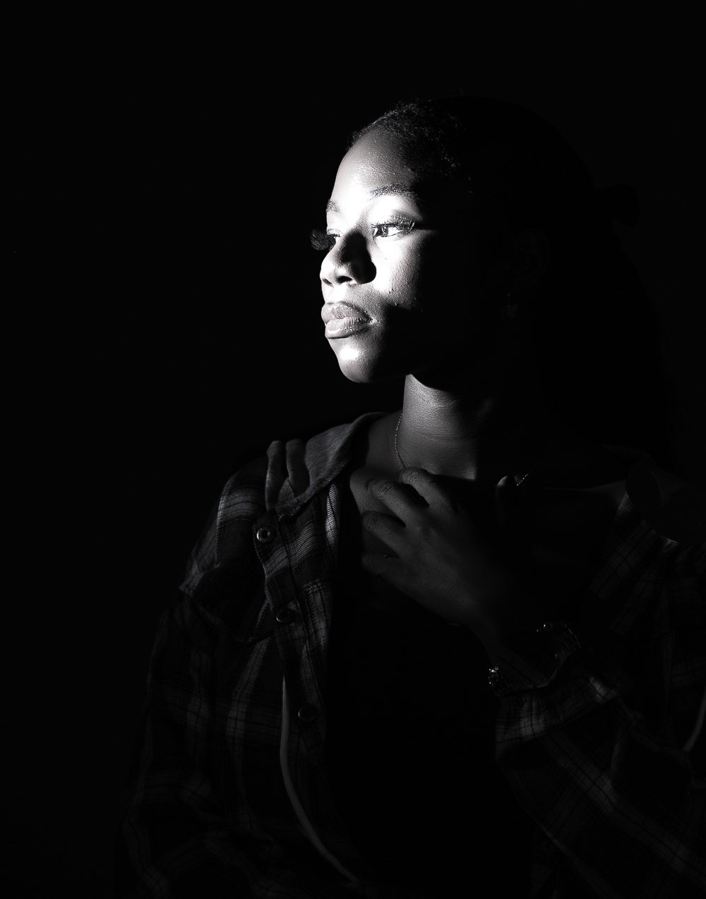 Dramatic studio portrait of a woman lit from the side against a dark background